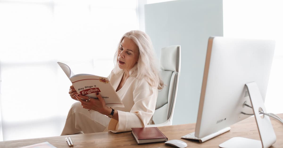 Vrouw studeert Nederlands voor het inburgeringsexamen A2 aan een tafel met boeken en laptop