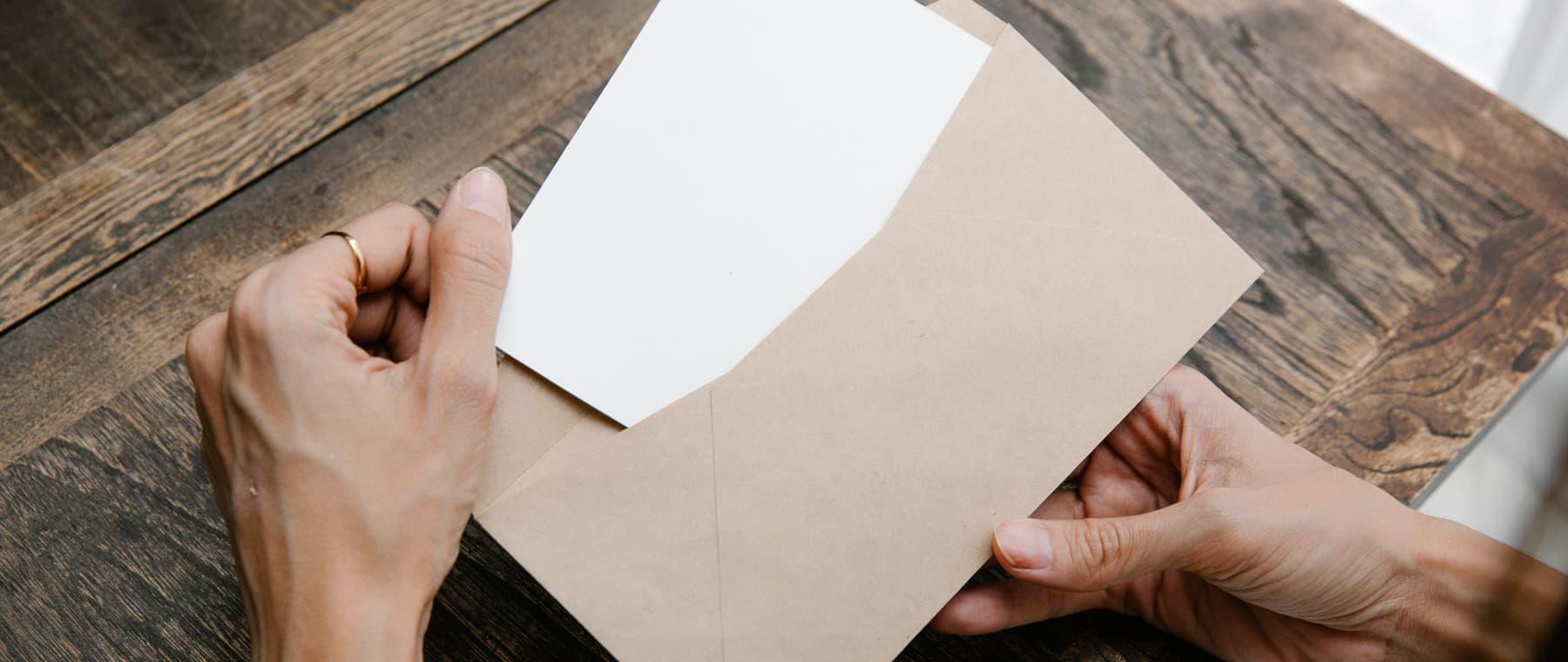Iemand haalt een brief uit een envelop op een houten tafel
