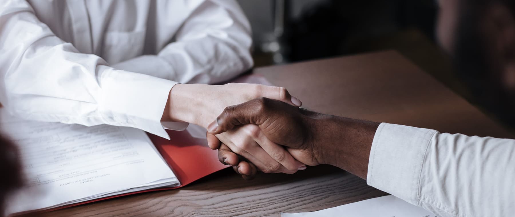Twee mensen geven elkaar een hand boven een tafel