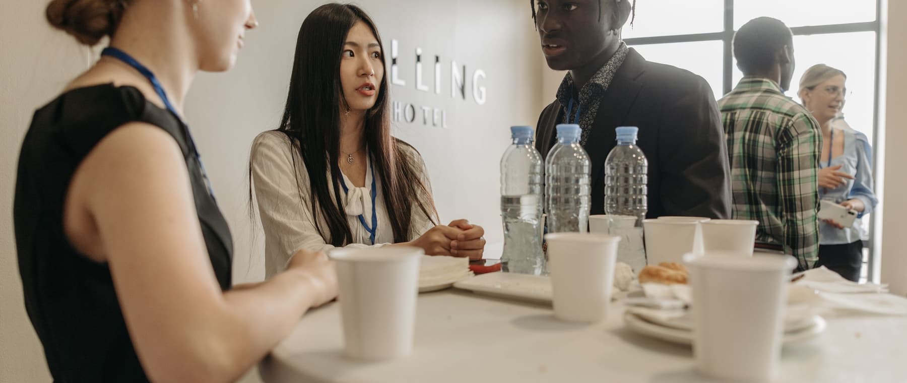 Een groep mensen staat samen rond een tafel te praten